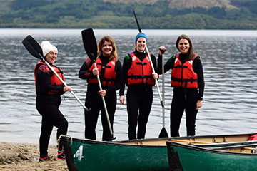 A group on the beach with canoes by Loch Lomond