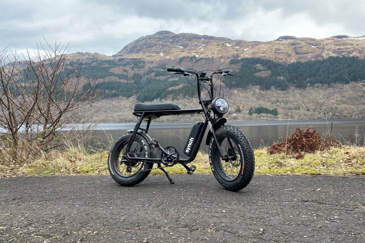 Electric bike on a road with lake and mountains in the background.