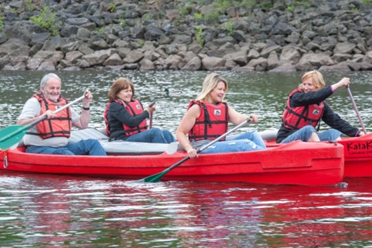 Four people in red canoe paddling on a calm river.